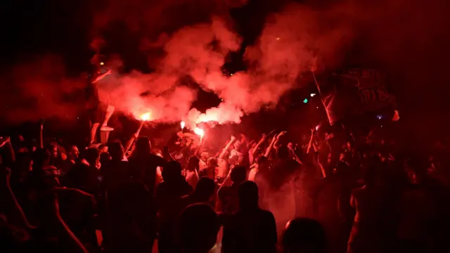 PSG taraftarları Paris'te polisle çatışmalar sırasında meşaleler yakarken.